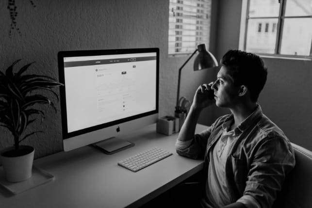 A man utilizing web design services sitting at a desk looking at a computer screen.