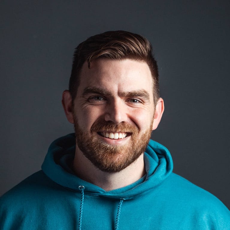 A man in a blue hoodie smiling.