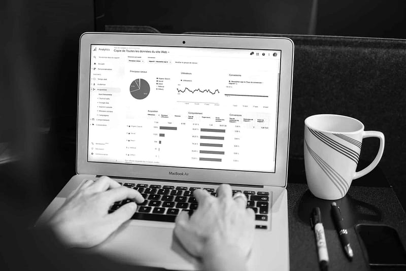 A person using a laptop for web design services while examining a graph on it.
